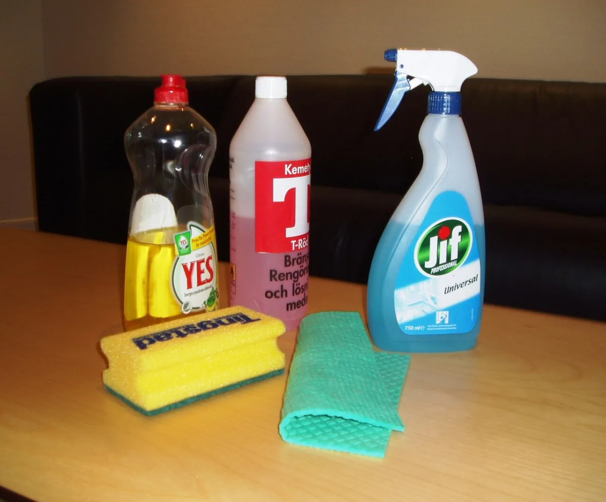 Schoonmaakmiddelen, een spons en een doekje op een tafel